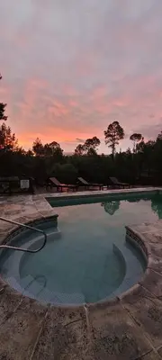 a large swimming pool with a sunset in the background at Aldea de los Cerros in Villa Yacanto