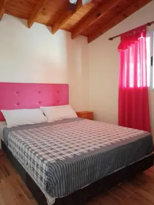 a bedroom with a bed with a pink headboard at Casa Miranda in Merlo
