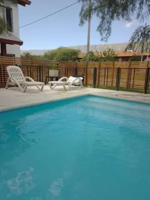 a swimming pool with two white chairs next to a fence at Casa Miranda in Merlo