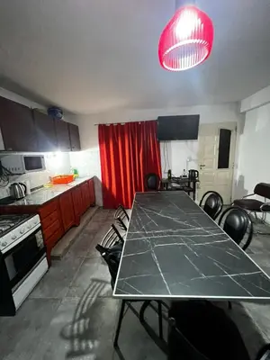 a kitchen with a table and a red curtain at Casita de los recuerdos in Villa Carlos Paz