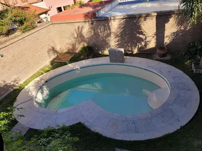 an empty swimming pool in a yard next to a brick wall at Gravensteen Urca in Cordoba
