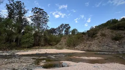 a river with rocks and trees on a hill at Cabañas Yarel in Alpa Corral