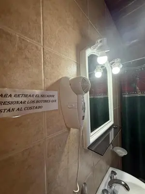 a bathroom with a blow dryer and a mirror at Cabañas Pindahue - Alojamiento Huilen in Villa Carlos Paz
