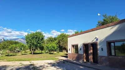 a white building with a door next to a field at Napoles complejo in Villa de Las Rosas