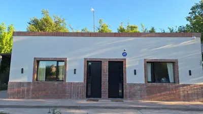 a white building with two windows and a door at Napoles complejo in Villa de Las Rosas