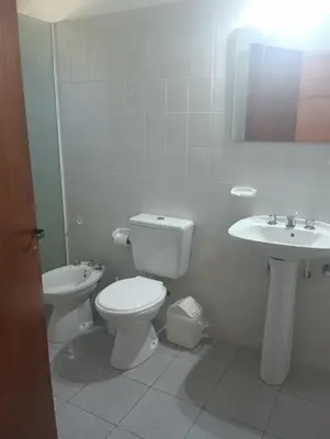 a white bathroom with a toilet and a sink at Los Algarrobos in Bialet Massé