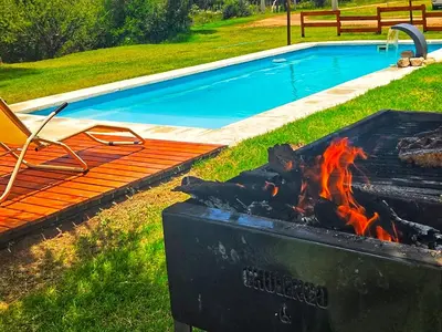 a barbecue next to a swimming pool with a chair and a chair at La Jocunda - Cortaderas - Piscu Yaco in Cortaderas