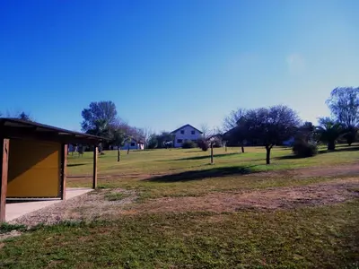 a park with a building and a field with trees at Lomas de Belgrano in Villa General Belgrano