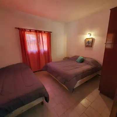 a bedroom with two beds and a window with red curtains at El Cartucho in Villa General Belgrano