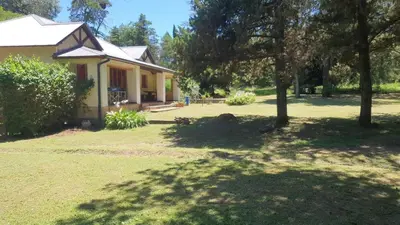 a house with a tree in front of a yard at El Cartucho in Villa General Belgrano