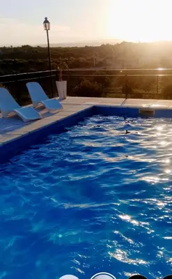 a swimming pool with lounge chairs and the sun setting at Encanto Serrano II in Villa Carlos Paz