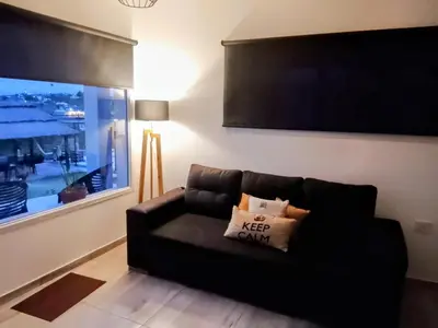 a black couch in a living room with a window at Encanto Serrano II in Villa Carlos Paz