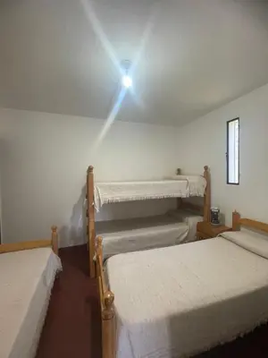 a room with three beds and a light on the ceiling at La Charito in Villa Cura Brochero