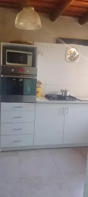 a kitchen with white cabinets and a microwave at Casa on the rock's in Nono