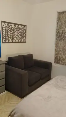 a brown couch sitting in a living room next to a bed at Departamento con cochera terraza y asador in Cordoba