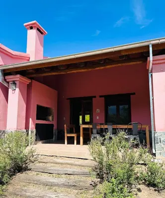 a red house with a patio and a table at La Buyi, Casa de Campo mirando al Champaqui in San Javier