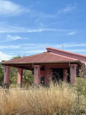 a pink building with a red roof on a field at La Buyi, Casa de Campo mirando al Champaqui in San Javier