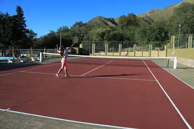 two women playing tennis on a tennis court at El Condor Hotel SPA in Merlo