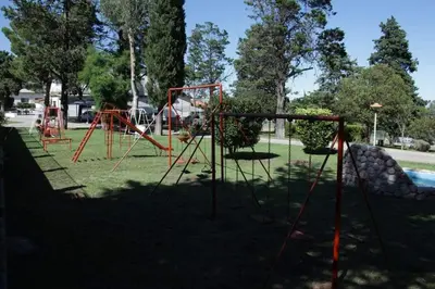 a park with an empty playground in the shade at El Condor Hotel SPA in Merlo