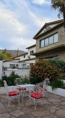three chairs and a table in front of a building at El Condor Hotel SPA in Merlo