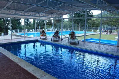 a group of people sitting in chairs by a swimming pool at El Condor Hotel SPA in Merlo