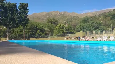 a pool with blue water and mountains in the background at El Condor Hotel SPA in Merlo