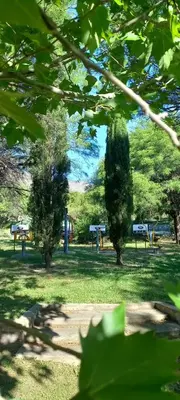 a park with trees and benches in the grass at Complejo Pasos Malos in Merlo