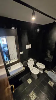 a bathroom with two toilets and a sink and a mirror at Elegante Depto 1 dorm pleno centro! in Cordoba