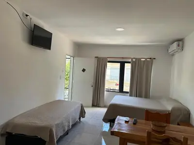 a room with two beds and a table and a tv at departamentos apart quetzal in Villa Carlos Paz