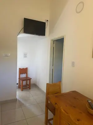 a living room with a table and a tv on the wall at departamentos apart quetzal in Villa Carlos Paz