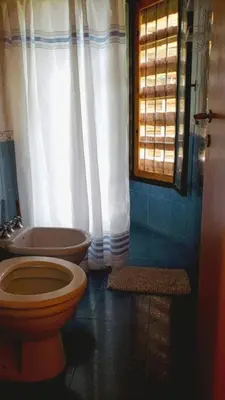 a bathroom with a toilet and a sink and a window at Casa de Campo in Santa Rosa de Calamuchita