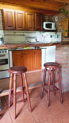 a kitchen with two wooden stools in front of a counter at Casa de Campo in Santa Rosa de Calamuchita