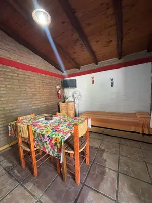 a dining room with a table and a bed at Cabañas La Lila in Santa Rosa de Calamuchita