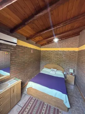 a bedroom with a bed in a brick wall at Cabañas La Lila in Santa Rosa de Calamuchita