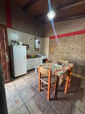 a kitchen with a table and a refrigerator at Cabañas La Lila in Santa Rosa de Calamuchita