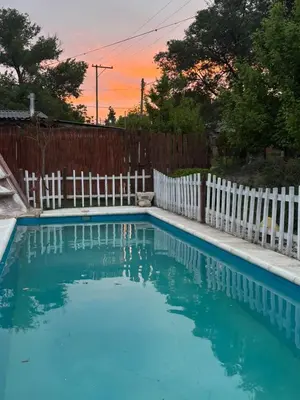 a swimming pool next to a white fence at Cabañas La Lila in Santa Rosa de Calamuchita