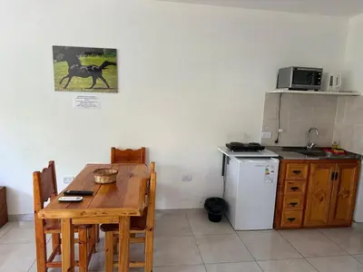 a kitchen with a wooden table and a refrigerator at Quetzal Apart Central Apartment N 3 in Villa Carlos Paz