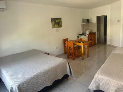 a bedroom with two beds and a table and a kitchen at Quetzal Apart Central Apartment N 3 in Villa Carlos Paz