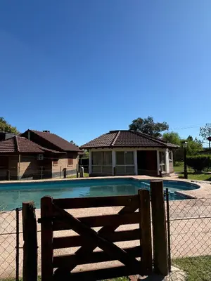 a swimming pool with a fence and a house at Cabañas Lomas del mirador in Villa del Dique