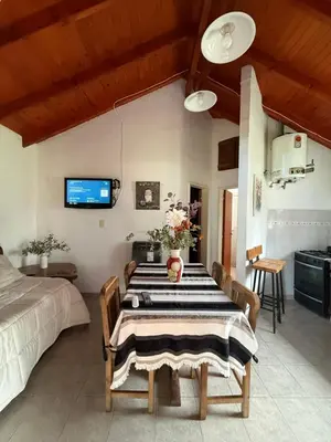 a dining room with a table and a kitchen at Cabañas Lomas del mirador in Villa del Dique