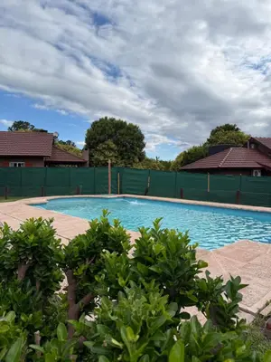 a large swimming pool with a green fence at Cabañas Lomas del mirador in Villa del Dique