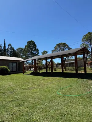 a wooden pavilion with a hose on the grass at Cabañas Lomas del mirador in Villa del Dique