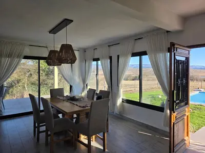 a dining room with a table and chairs and windows at havendq in Villa General Belgrano