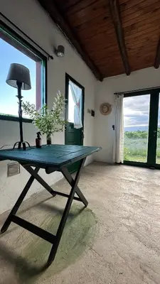 a table with a lamp in a room with windows at La Colorada de Yacanto in Villa Yacanto