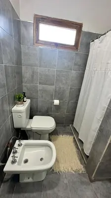 a bathroom with a toilet and a sink and a window at La Colorada de Yacanto in Villa Yacanto