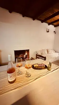 two glasses of wine on a table with a fireplace at La Colorada de Yacanto in Villa Yacanto