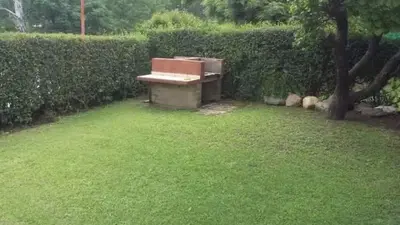 a park bench sitting in the grass next to a hedge at CastelAnte in Villa Carlos Paz