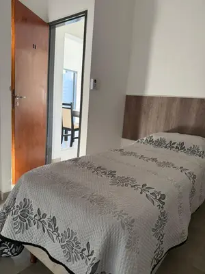 a bedroom with a bed with a white blanket at La Rosas apartments in La Porteña