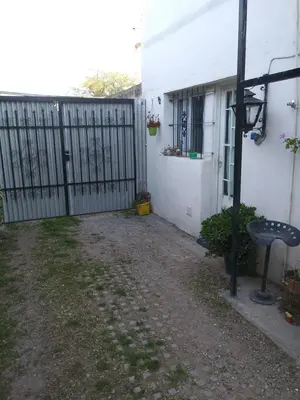 a fence next to a white house with a yard at Alojamiento Libertador in Alta Gracia
