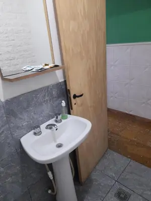 a bathroom with a white sink and a wooden door at Departamento por dia in Río Cuarto